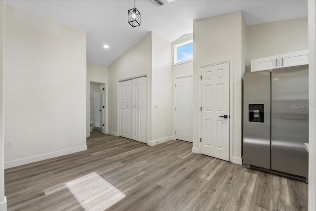 interior space with high vaulted ceiling, baseboards, and light wood-type flooring