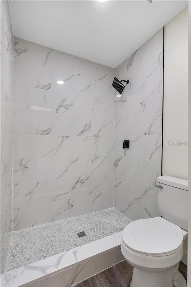full bathroom featuring wood finished floors, a stall shower, and toilet