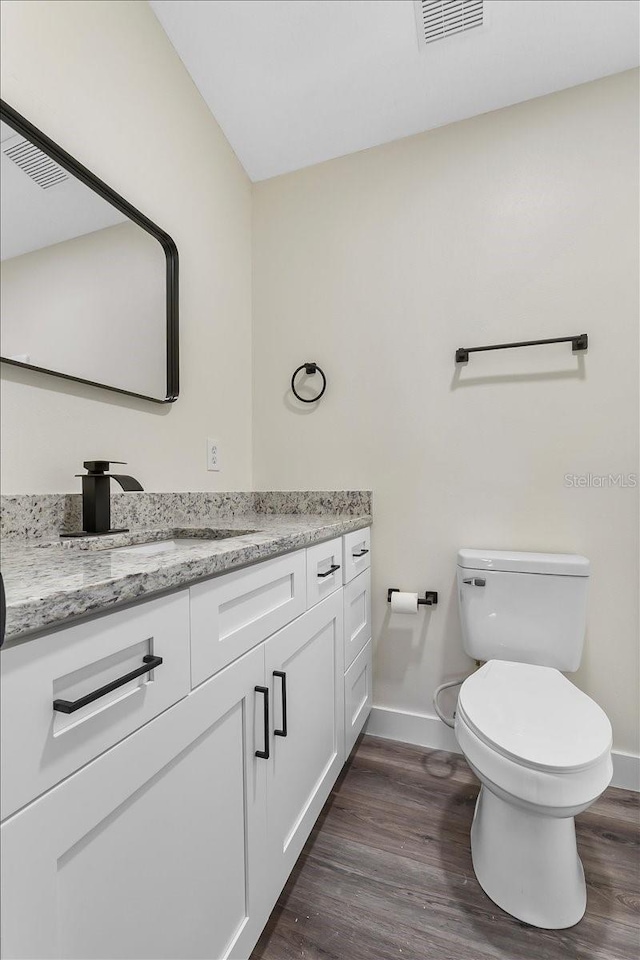 bathroom featuring visible vents, vanity, wood finished floors, toilet, and baseboards