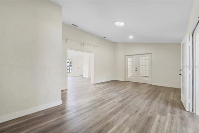 empty room featuring french doors, baseboards, and wood finished floors