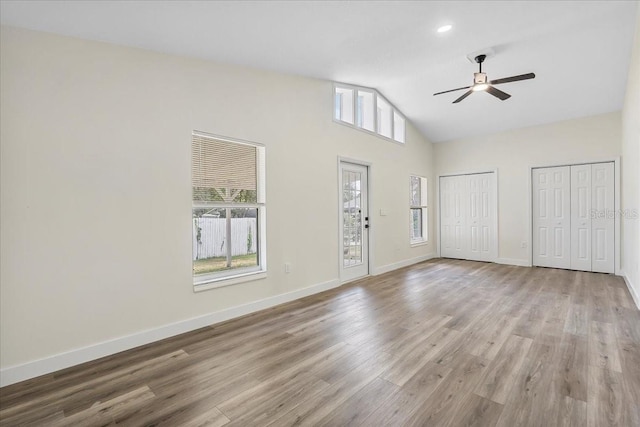 unfurnished living room with baseboards, a ceiling fan, high vaulted ceiling, and wood finished floors