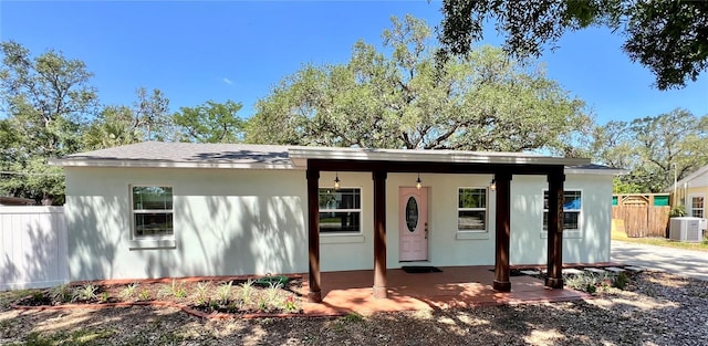 view of front facade with fence, central air condition unit, stucco siding, and a porch