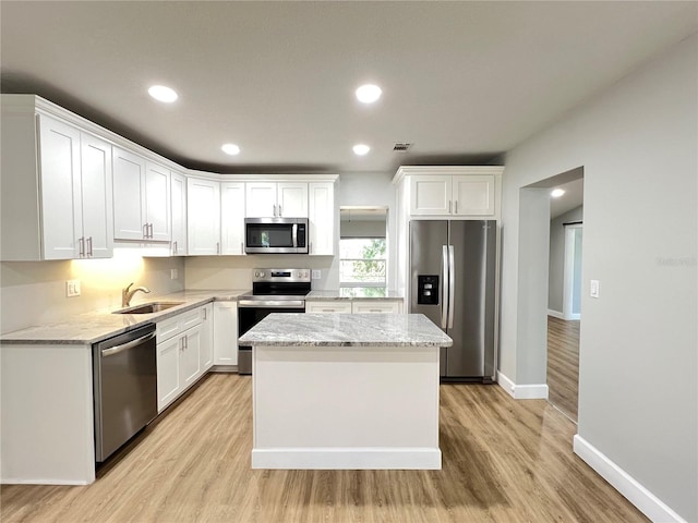 kitchen with light wood finished floors, a sink, white cabinetry, and stainless steel appliances