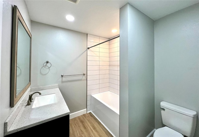 full bathroom featuring wood finished floors, toilet, vanity, baseboards, and washtub / shower combination