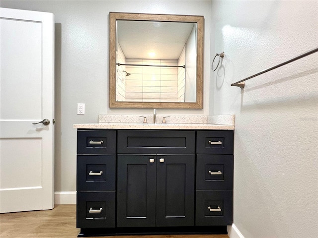 bathroom with wood finished floors, vanity, and baseboards