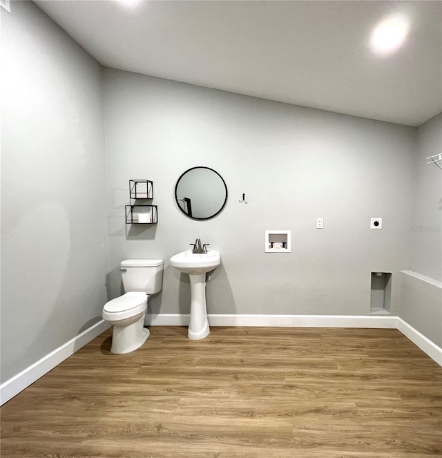 bathroom featuring baseboards, wood finished floors, and toilet
