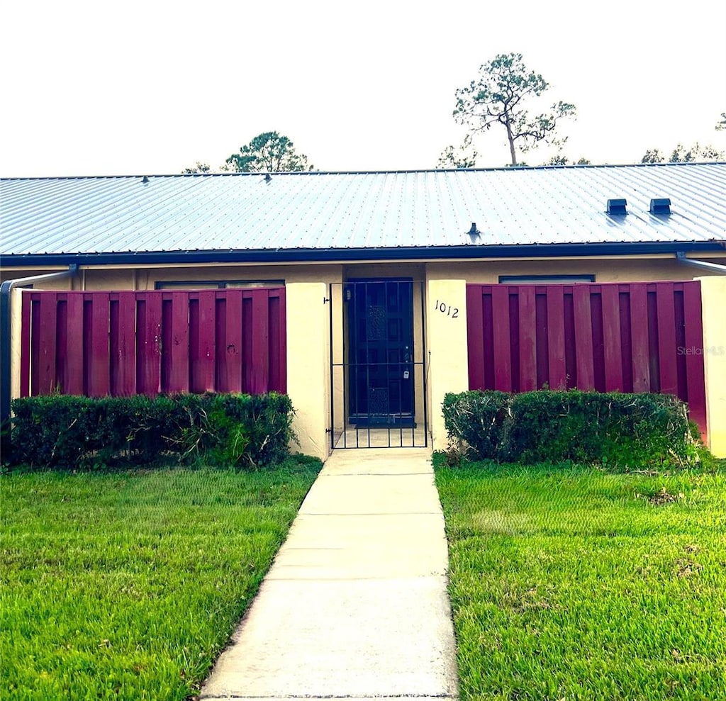 exterior space featuring stucco siding, metal roof, and a front yard