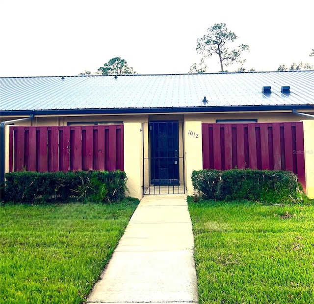 exterior space featuring stucco siding, metal roof, and a front yard