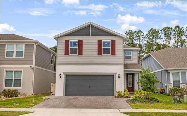 traditional home with an attached garage, decorative driveway, stucco siding, and a front yard