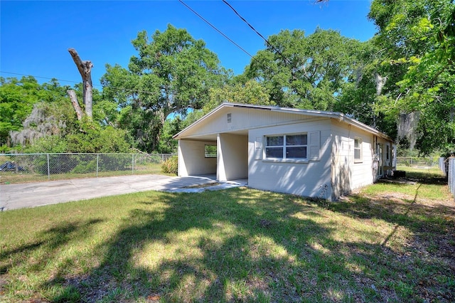 bungalow-style house featuring concrete driveway, an attached carport, fence, and a front lawn