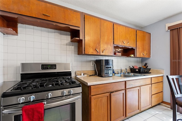 kitchen with gas stove, light countertops, decorative backsplash, and a sink