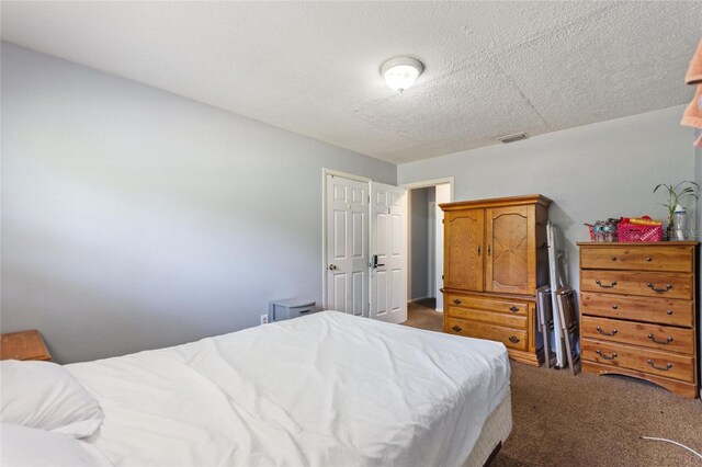 bedroom with carpet floors, a textured ceiling, and visible vents