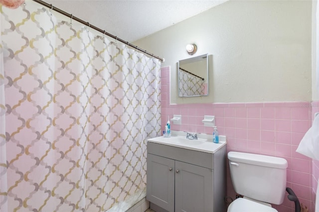 full bathroom with tile walls, curtained shower, a wainscoted wall, vanity, and toilet