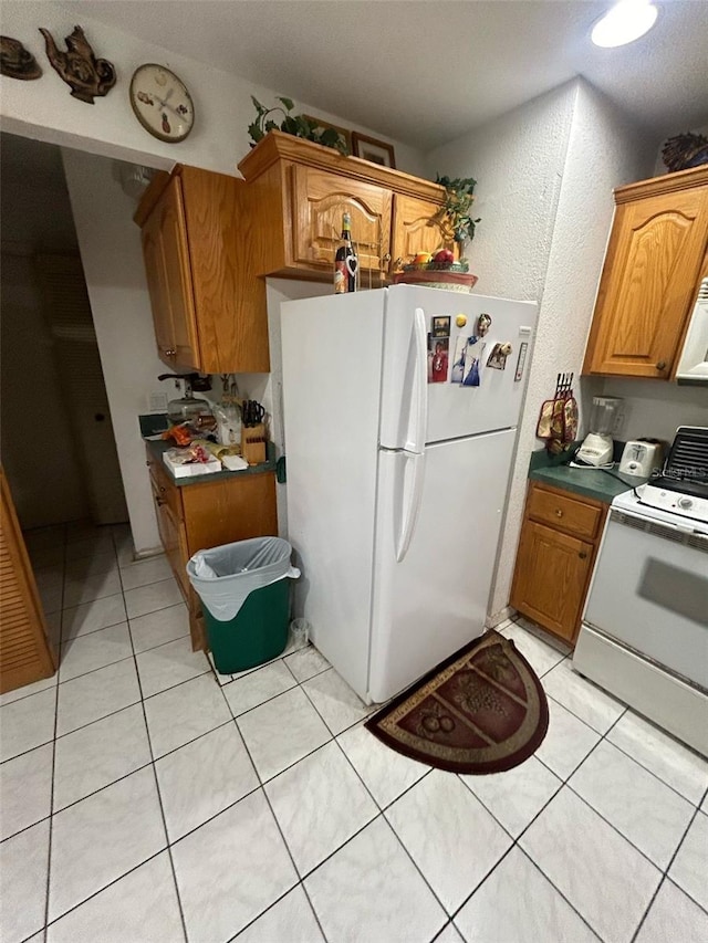 kitchen with light tile patterned floors, brown cabinets, and white appliances