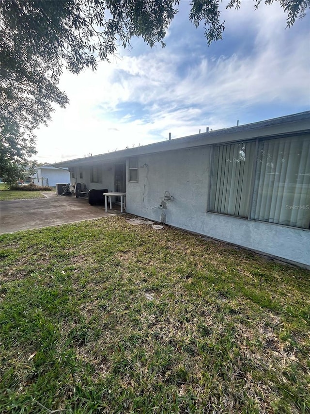 view of side of property with stucco siding and a yard