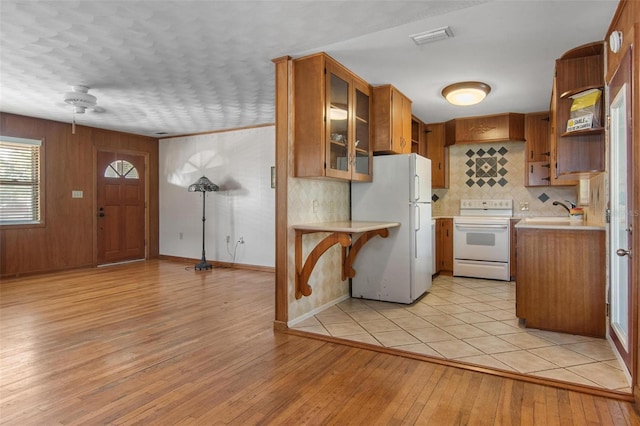1371 Sheridan St SW, Winter Haven, FL 33880 - kitchen with visible vents, brown cabinetry, white appliances, light countertops, and light wood finished floors