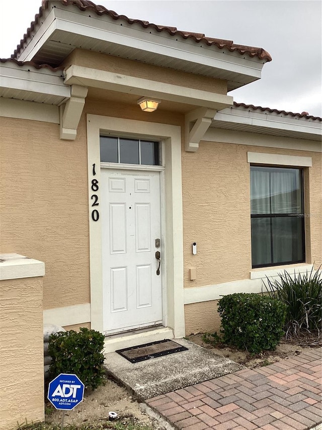 doorway to property with stucco siding and a tiled roof