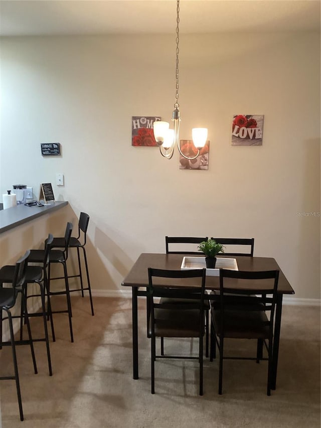 carpeted dining space featuring baseboards and a chandelier