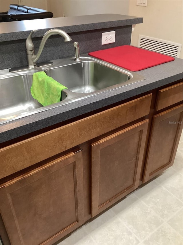 interior details featuring dark countertops, visible vents, brown cabinetry, and a sink