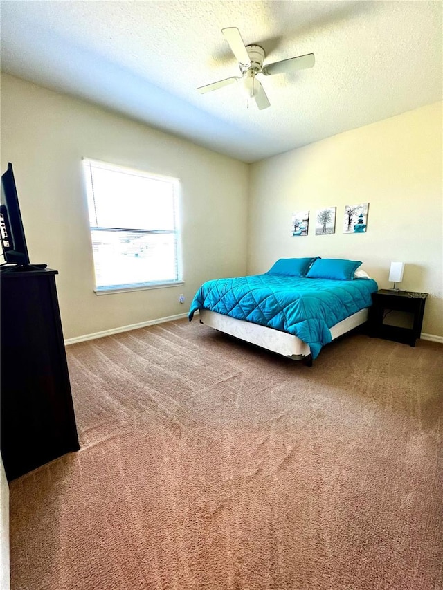 carpeted bedroom featuring a textured ceiling, baseboards, and ceiling fan