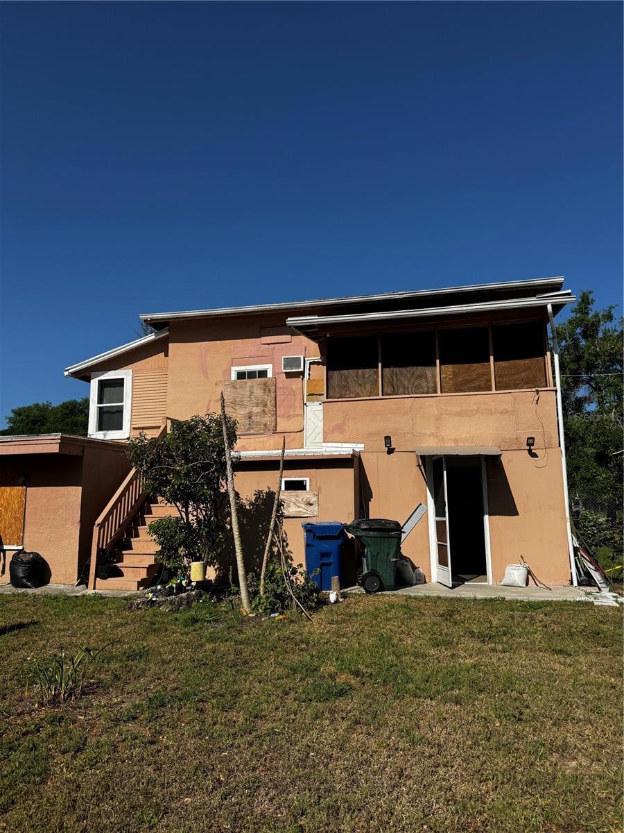 229 NE Ave B, Winter Haven, FL 33881 - rear view of property featuring a lawn, stairs, and stucco siding