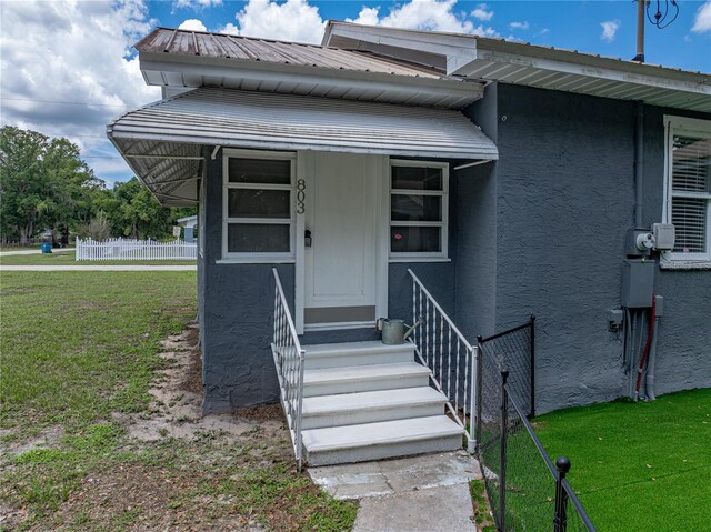 803 7th St NE, Fort Meade, FL 33841 - view of exterior entry with stucco siding and metal roof
