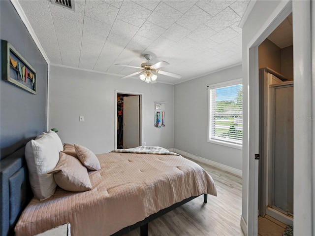 803 7th St NE, Fort Meade, FL 33841 - bedroom with wood finished floors, ornamental molding, a ceiling fan, a walk in closet, and baseboards