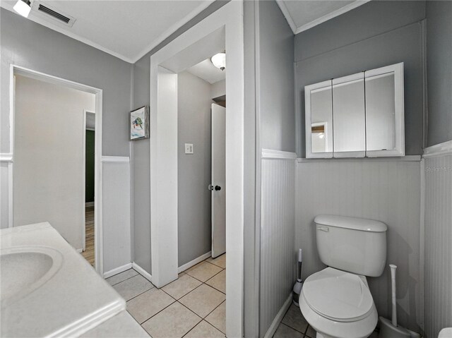 803 7th St NE, Fort Meade, FL 33841 - bathroom featuring toilet, wainscoting, vanity, ornamental molding, and tile patterned flooring