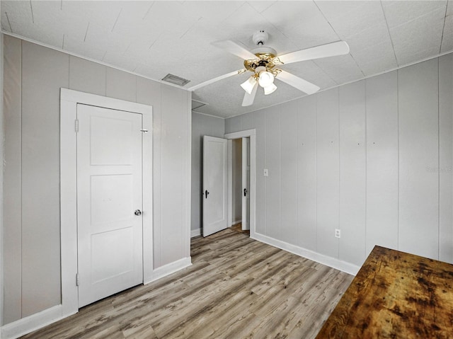 803 7th St NE, Fort Meade, FL 33841 - unfurnished bedroom with wood finished floors, baseboards, ceiling fan, and a decorative wall