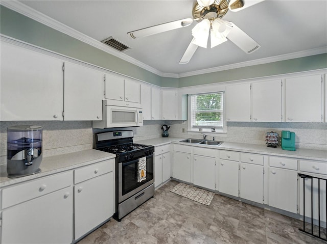 803 7th St NE, Fort Meade, FL 33841 - kitchen featuring stainless steel gas range oven, white microwave, a sink, ornamental molding, and white cabinets