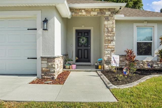 view of exterior entry with stucco siding, roof with shingles, stone siding, and a garage