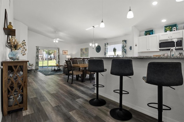 kitchen featuring stainless steel microwave, a breakfast bar, dark wood-style flooring, and white cabinetry