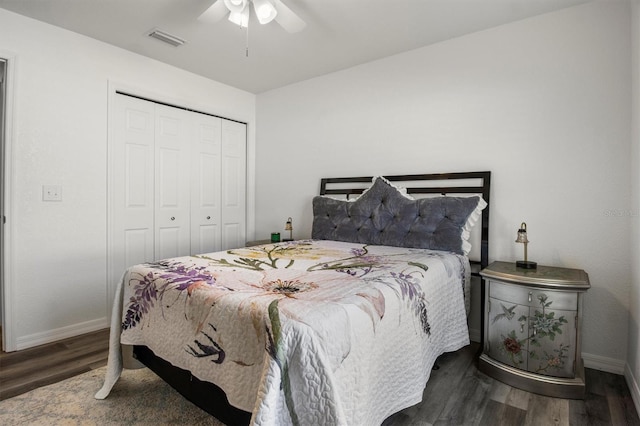 bedroom with a ceiling fan, visible vents, wood finished floors, baseboards, and a closet