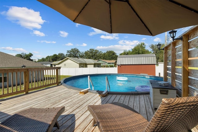 view of pool with a fenced in pool, an outdoor structure, a deck, and a shed