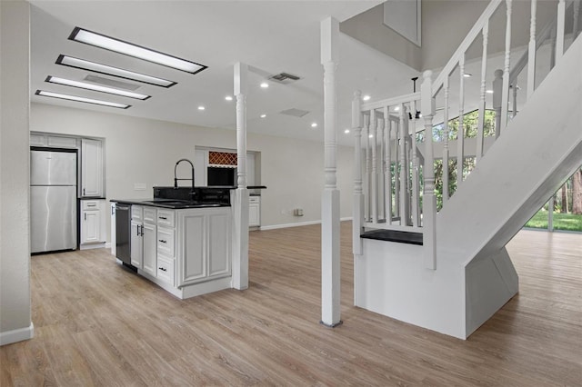 6317 Discovery Ln, Land O Lakes, FL 34638 - kitchen with visible vents, dark countertops, light wood-type flooring, a sink, and appliances with stainless steel finishes
