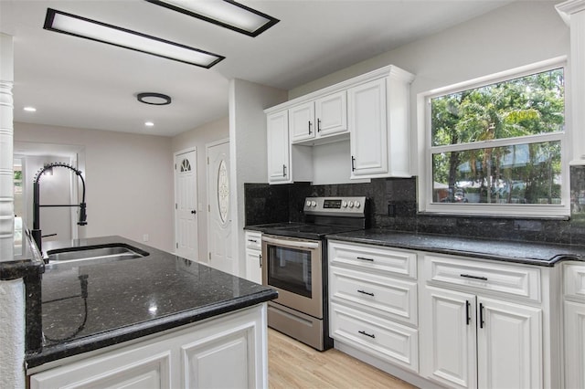 6317 Discovery Ln, Land O Lakes, FL 34638 - kitchen with light wood-style floors, dark stone counters, stainless steel electric range, white cabinetry, and a sink