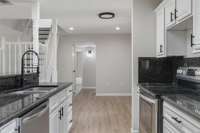 6317 Discovery Ln, Land O Lakes, FL 34638 - kitchen with appliances with stainless steel finishes, a sink, white cabinets, light wood finished floors, and dark stone countertops