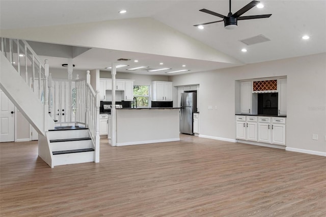6317 Discovery Ln, Land O Lakes, FL 34638 - unfurnished living room with stairs, vaulted ceiling, visible vents, and light wood-type flooring