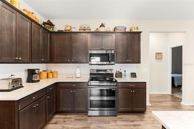 kitchen with light countertops, stainless steel appliances, light wood-type flooring, and dark brown cabinets