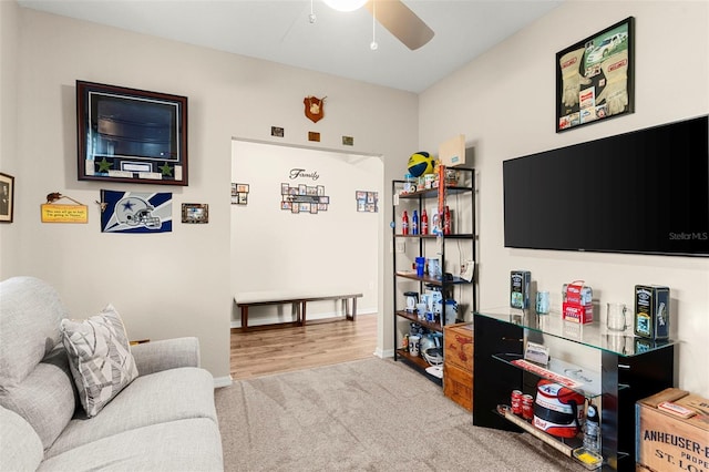 carpeted living area featuring baseboards and a ceiling fan