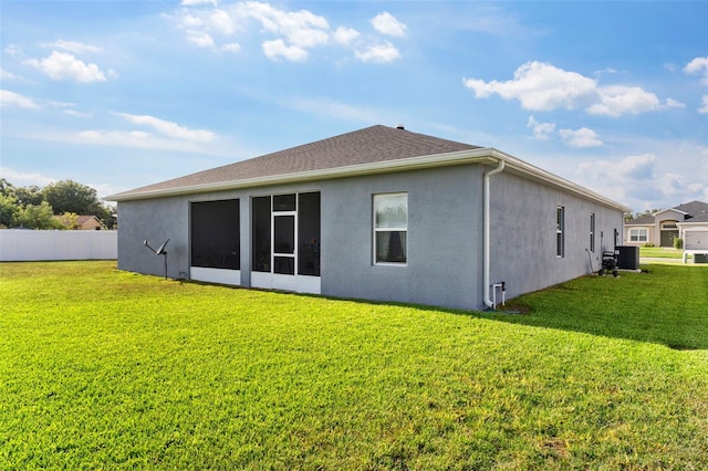 rear view of house featuring a lawn, fence, central air condition unit, and stucco siding