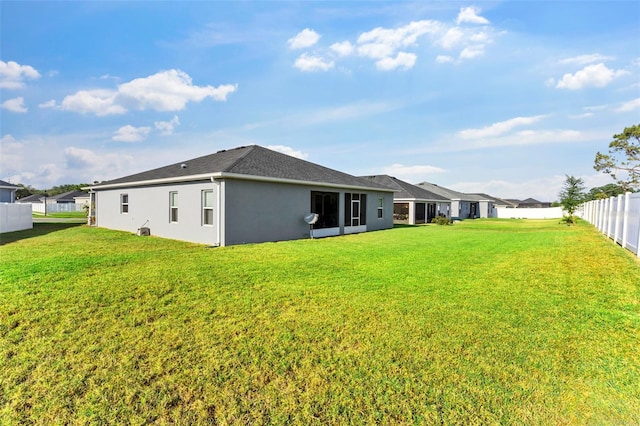 back of house featuring fence, stucco siding, and a yard