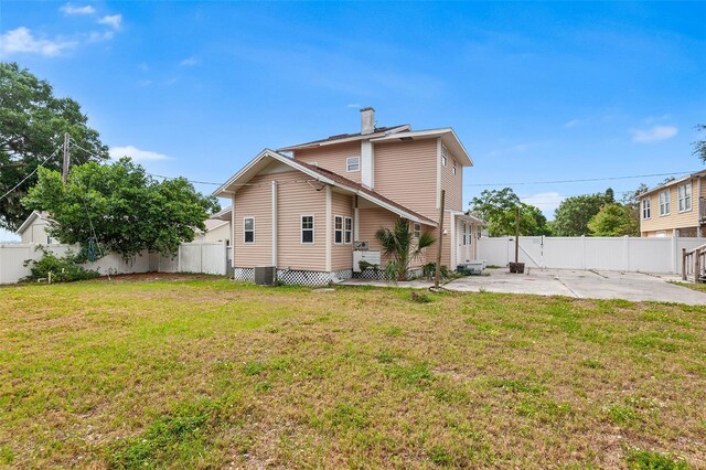 rear view of property featuring a lawn, a fenced backyard, a patio area, and a chimney