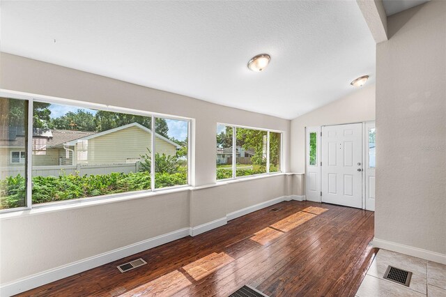 foyer with baseboards, vaulted ceiling, hardwood / wood-style flooring, and visible vents