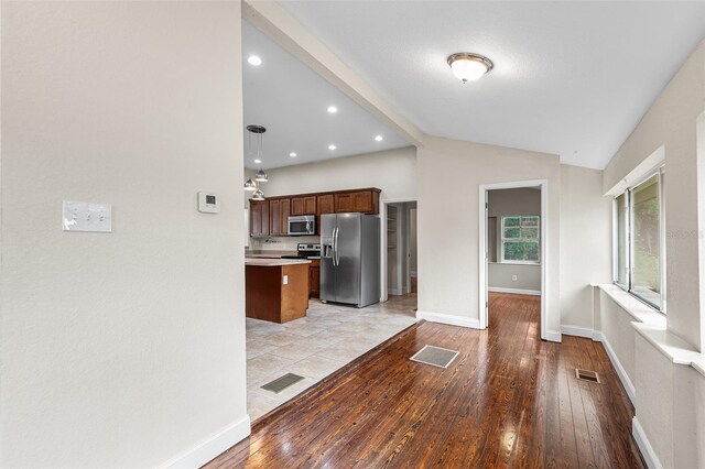 kitchen with visible vents, vaulted ceiling, light countertops, stainless steel appliances, and light wood-style flooring