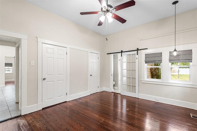 unfurnished bedroom with hardwood / wood-style floors, baseboards, and a barn door