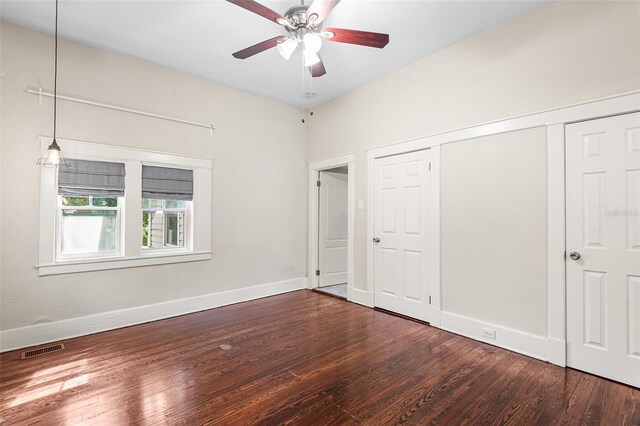 unfurnished bedroom featuring visible vents, a closet, wood finished floors, baseboards, and a ceiling fan