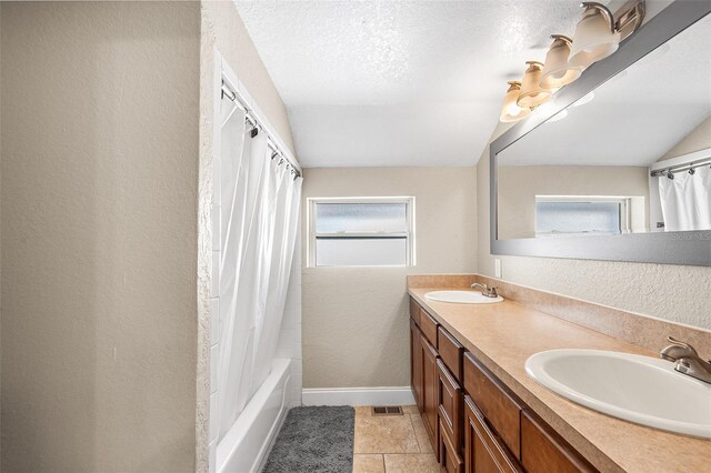 full bath featuring a sink, a textured wall, and a wealth of natural light