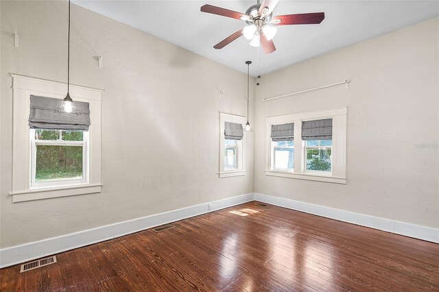 empty room featuring visible vents, a ceiling fan, baseboards, and wood finished floors