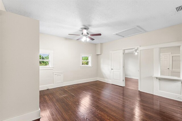 unfurnished bedroom featuring hardwood / wood-style floors, baseboards, attic access, ceiling fan, and a textured ceiling